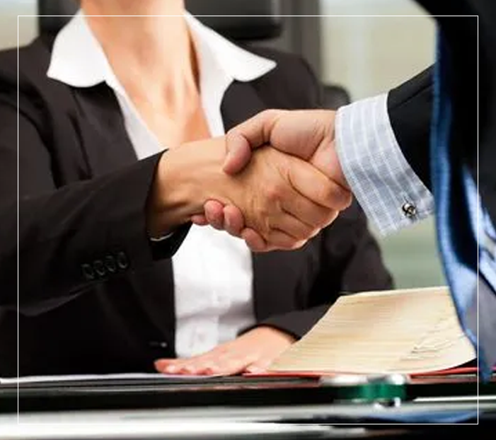 Two people shaking hands over a table.