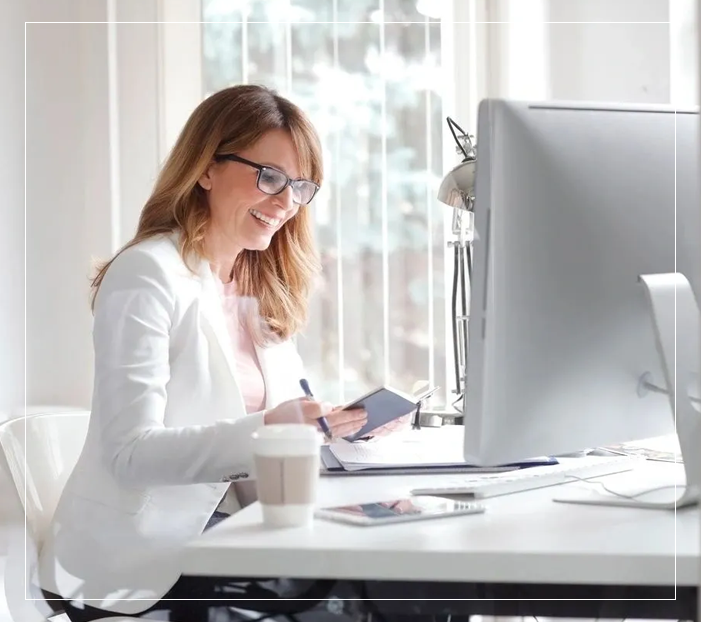 A woman sitting at her desk with a cup of coffee.